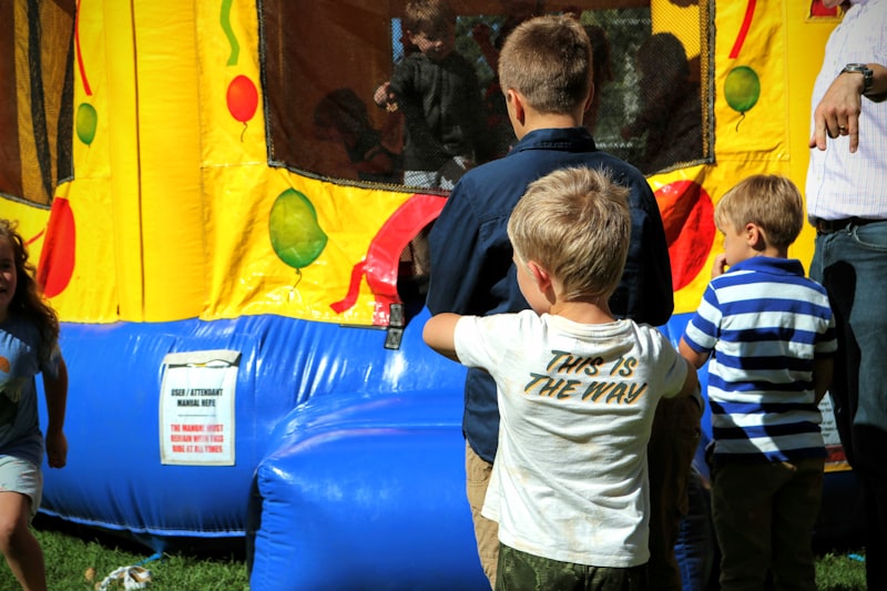 Kids waiting to jump in a standard yellow and blue bounce house rental